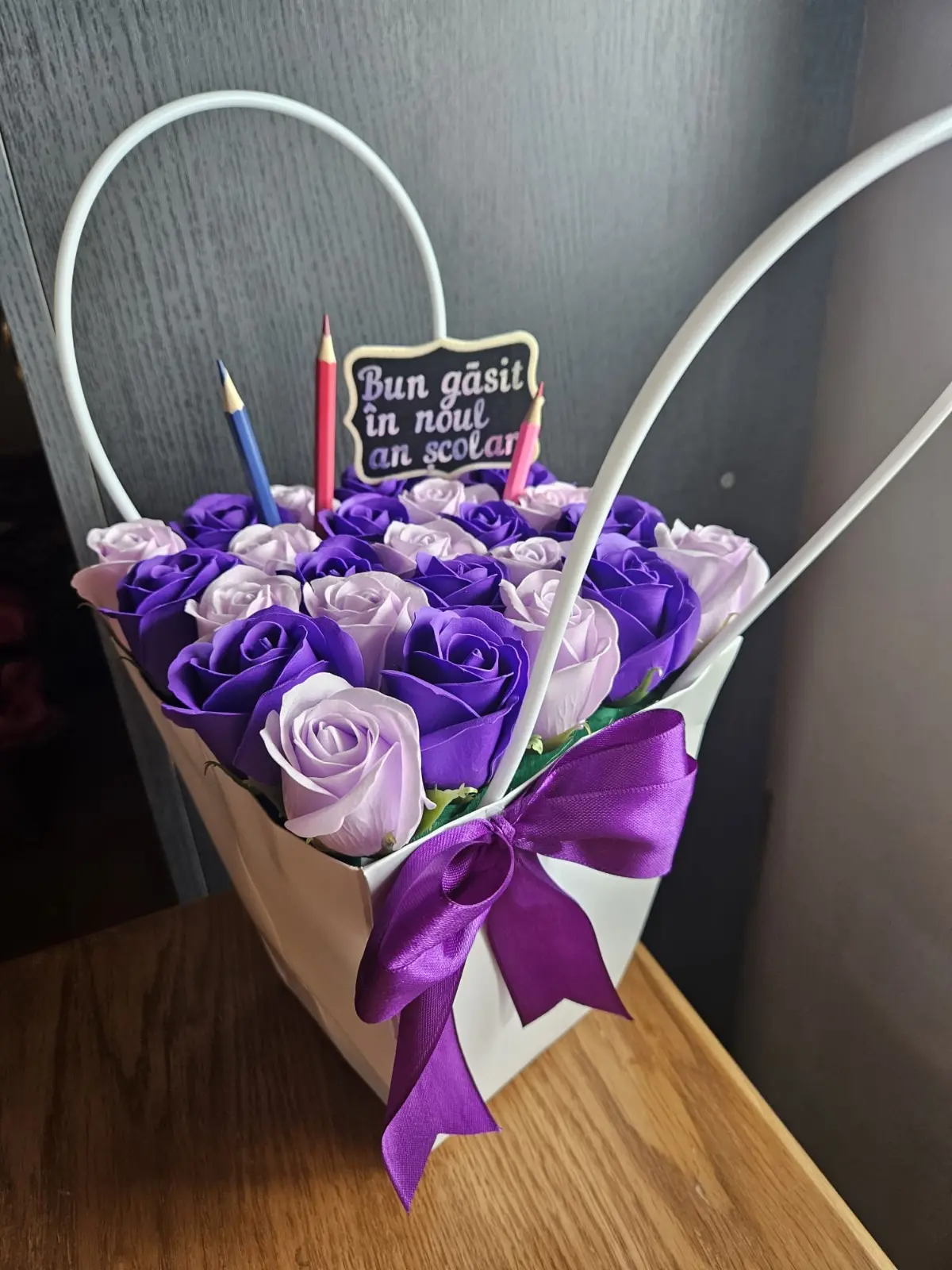 Coșuleț cu 25 de trandafiri de săpun mov, lila și albi, fundă mov din satin și topper „Bun găsit în noul an școlar”