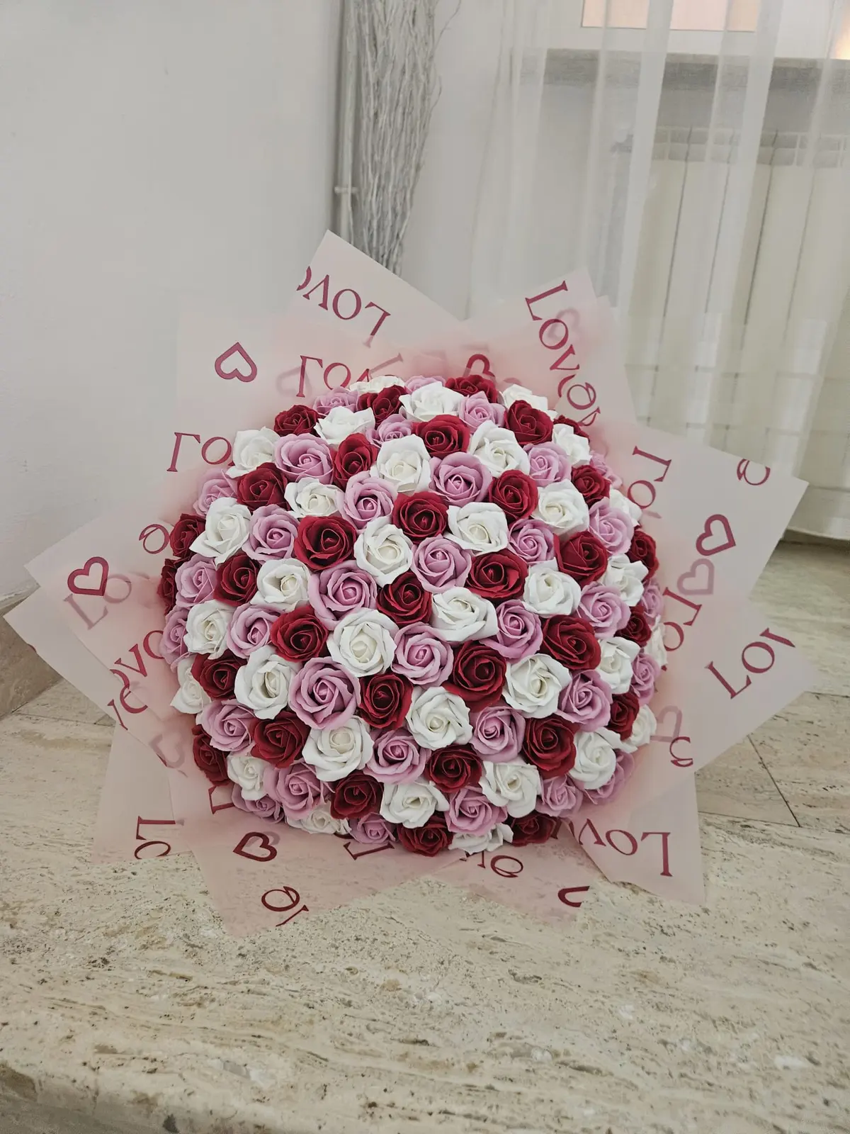 Buchet din trandafiri de săpun roșii, albi și lila așezați în model de mozaic, în ambalaj roz pastel
