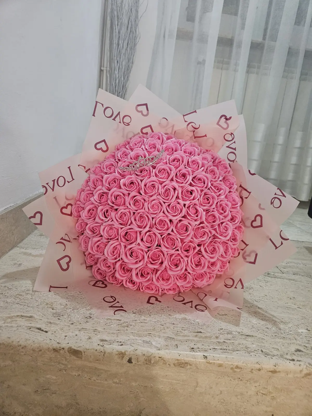 Buchet generos din trandafiri de săpun roz pudrat, cu tiară argintie, în ambalaj roz cu inimioare